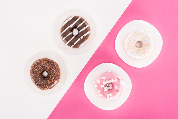 bovenaanzicht van verschillende lekkere donuts op platen - Foto, afbeelding