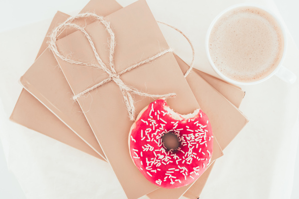 bovenaanzicht van donut op wrapper pakketten met kopje koffie - Foto, afbeelding