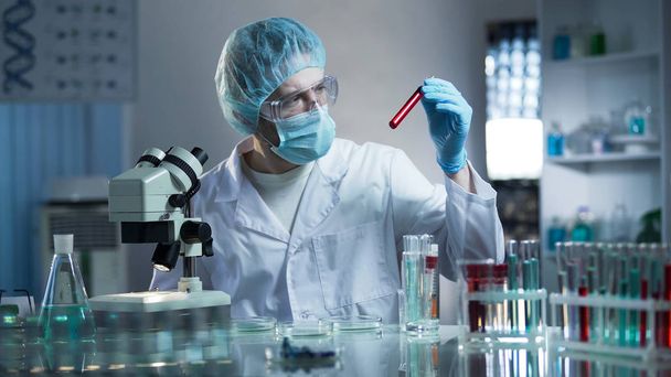 Laboratory worker studying blood samples to detect pathologies, medical research - 写真・画像