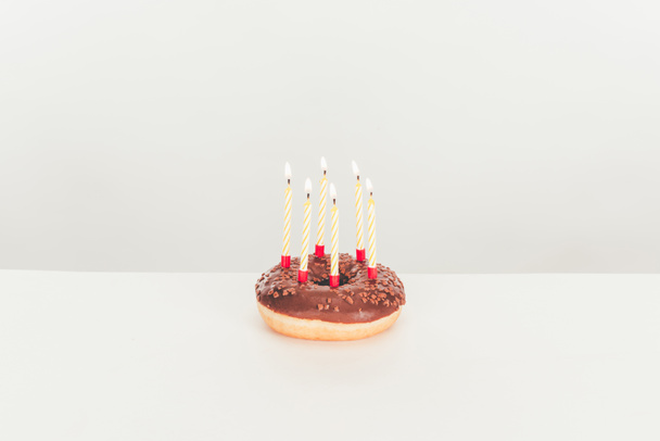 heerlijke geglazuurde donut met birthday kaarsen op witte tafel - Foto, afbeelding