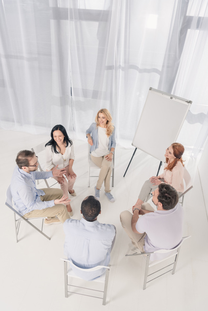 high angle view of middle aged people sitting on chairs and talking during group therapy - Photo, Image