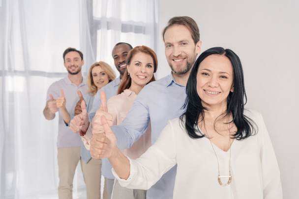 middle aged people smiling at camera and showing thumbs up during group therapy   - Photo, Image