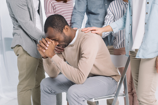tiro recortado de pessoas que apoiam deprimido homem afro-americano de meia-idade durante a terapia de grupo
  - Foto, Imagem