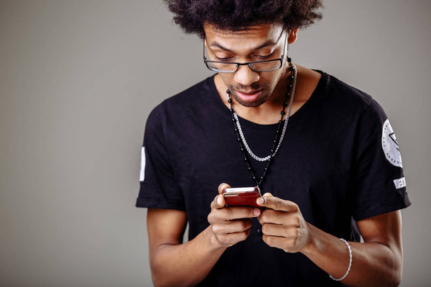 black male in trendy looking through pcitures via social media, using cell phone - Φωτογραφία, εικόνα