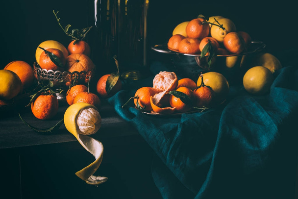 vista de perto de arranjo de limões frescos e tangerinas em tigela e filtro na mesa com toalha de mesa escura
 - Foto, Imagem
