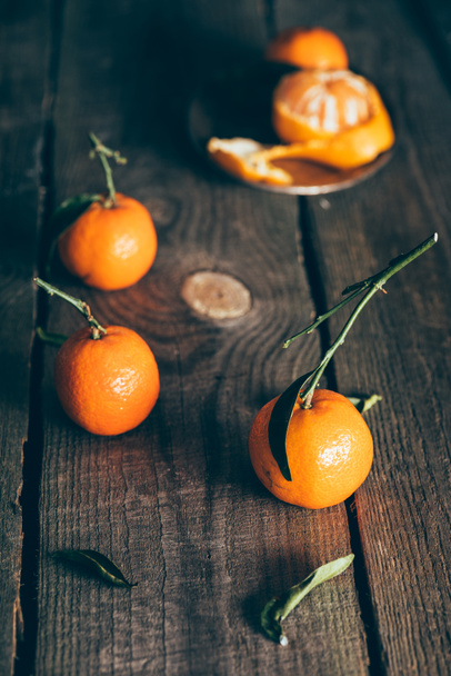 close up view of ripe mandarins with leaves on wooden tabletop - Foto, imagen