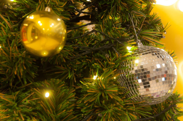 Декорування ялинки крупним планом. Лампочка для прикрас, зелена ялинка, золоті різдвяні іграшки та вогні. Використовувати для святкування Різдва та Нового року
 - Фото, зображення