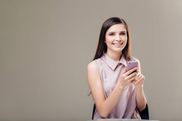 Retrato de una mujer casual sonriente sosteniendo el teléfono inteligente sobre fondo blanco - Foto, Imagen