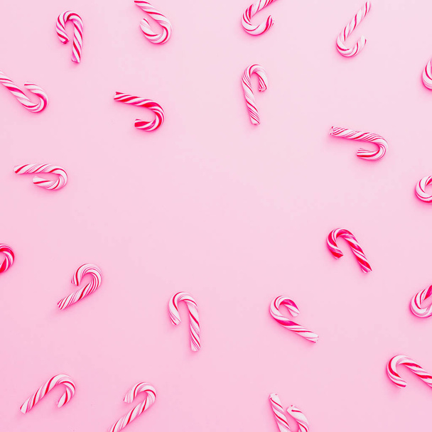伝統的なクリスマスのお菓子の杖に分離された、ピンクの背景コピー スペース。フラット横たわっていた休日の概念. - 写真・画像