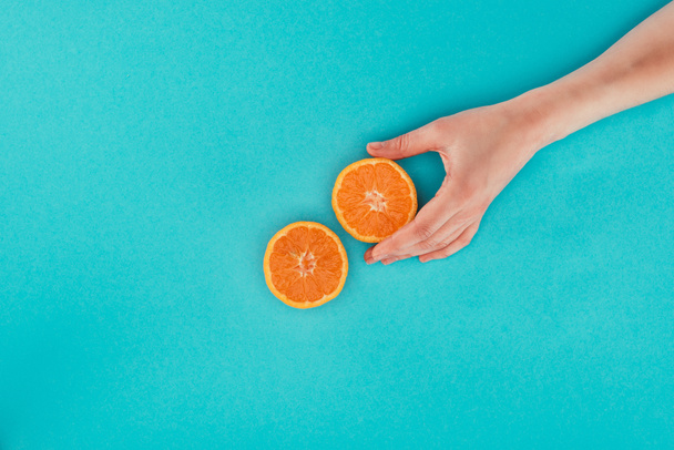 vue partielle de la femme tenant un morceau d'orange isolé sur bleu
 - Photo, image