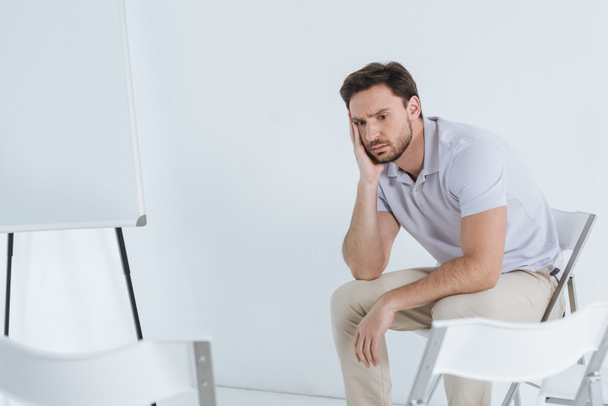depressed man sitting and looking away in empty room - Fotografie, Obrázek