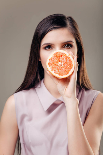 Young brunette with red grapefruit in her hand - Fotoğraf, Görsel
