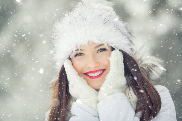 Beautiful smiling young woman in warm clothing. The concept of portrait in winter snowy weather - Photo, image