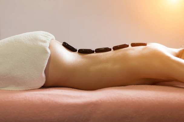 Spa Stone Massage. Hermosa mujer consiguiendo spa piedras calientes masaje en el salón de spa. - Foto, Imagen