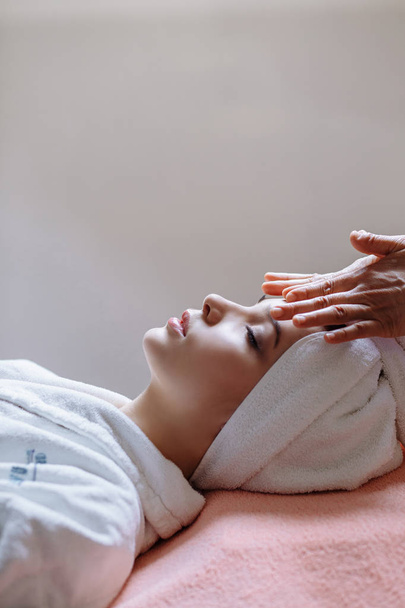 woman lying with closed eyes and having face or head massage in spa - Foto, Imagem