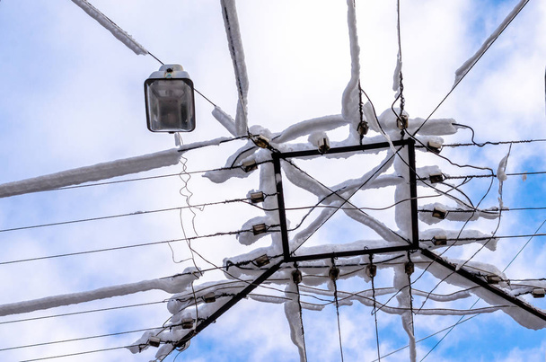 Transmission lines in snow and ice in the winter in the city on the background of the sky. Bad weather, catastrophe, third world country, natural disaster. - Photo, Image