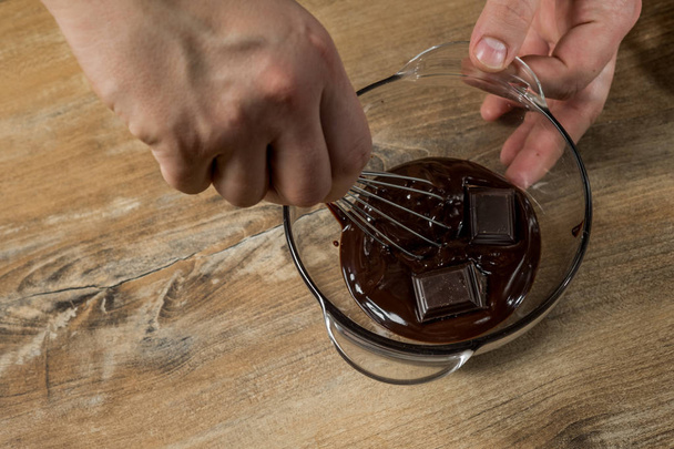 close-up of male hands mixing chocolate in bowl, prepare chocolate cake - Foto, Bild