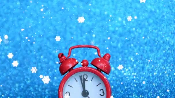 punainen kello heijastaa nopeasti vuoden viimeistä 5 minuuttia, onnellista uutta vuotta, sinistä taustaa ja lumihiutaleita
 - Materiaali, video