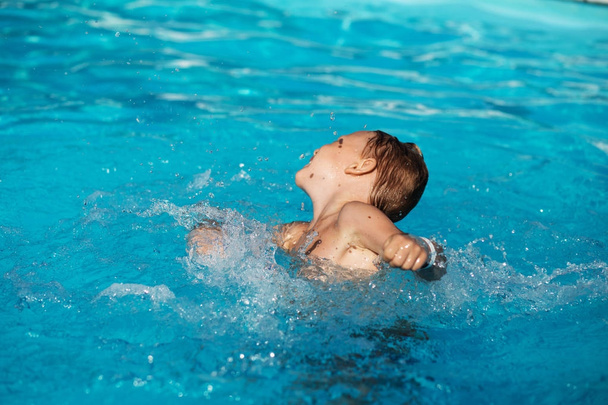 Ragazzo felice che gioca in acqua azzurra di piscina. pulce bambino
 - Foto, immagini