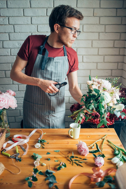 Young male florist working at counter in flower shop - Foto, immagini