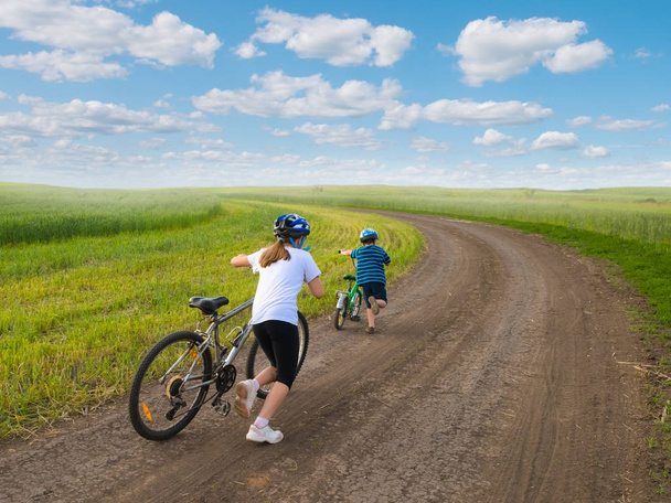 Sportliche Kinder laufen mit Fahrrädern bergauf - Foto, Bild