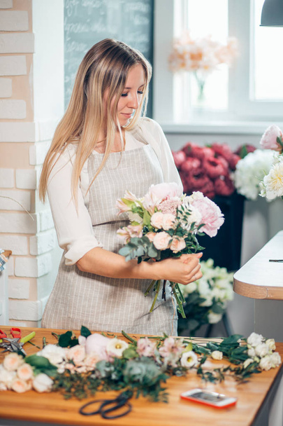 Happy beautiful young woman florist in glasses standing in flower shop - Foto, Imagem