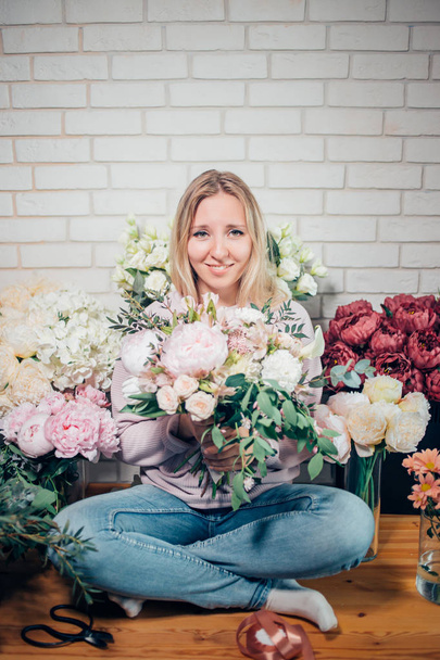 cheerful pretty young woman florist in glasses looking at camera in flower shop - Photo, Image