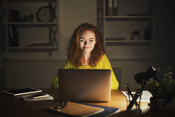 Freelancer werkt op laptop thuis tot laat in de avond - Foto, afbeelding