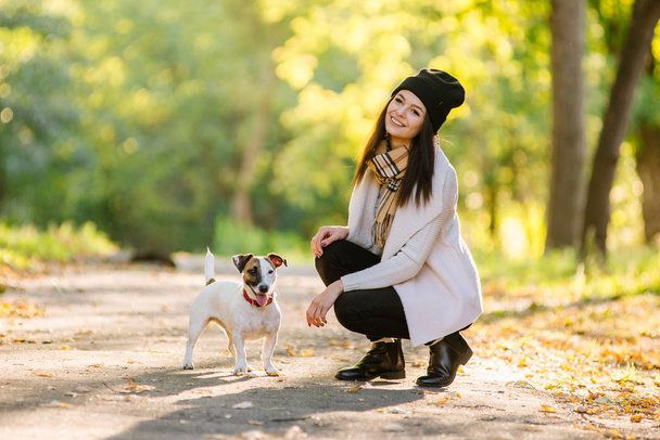 όμορφο κορίτσι είναι το περπάτημα με ένα σκυλί. Παίζει με το σκυλί για το πάρκο. - Φωτογραφία, εικόνα