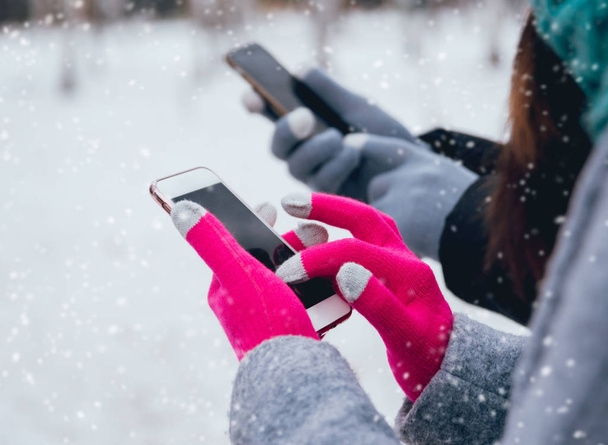 Couple using smartphone with gloves for touch screens in winter - Zdjęcie, obraz