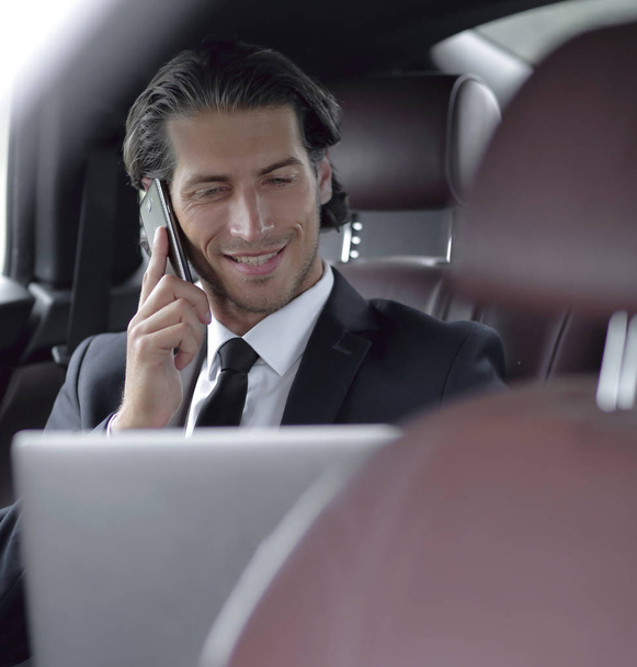 Handsome businessman using mobile phone in car. - Valokuva, kuva