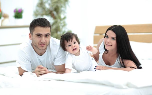 Retrato de familia joven y feliz acostados en la cama juntos
 - Foto, Imagen