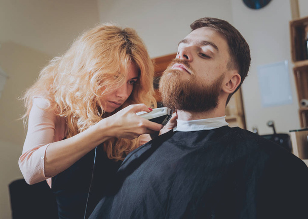 Meister schneidet Männern Haare und Bart, Friseur frisiert jungen Mann. - Foto, Bild