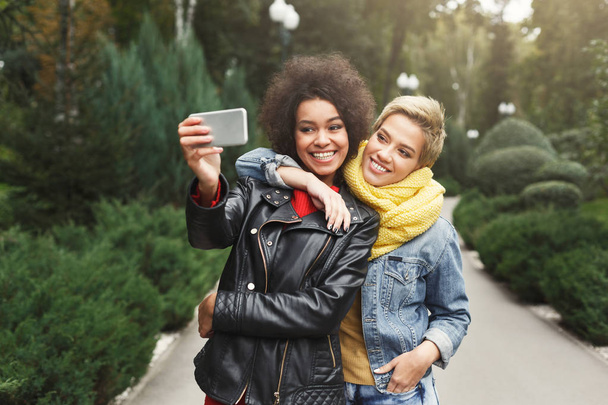 Onnellisia tyttöjä älypuhelimen kanssa ulkona puistossa
 - Valokuva, kuva