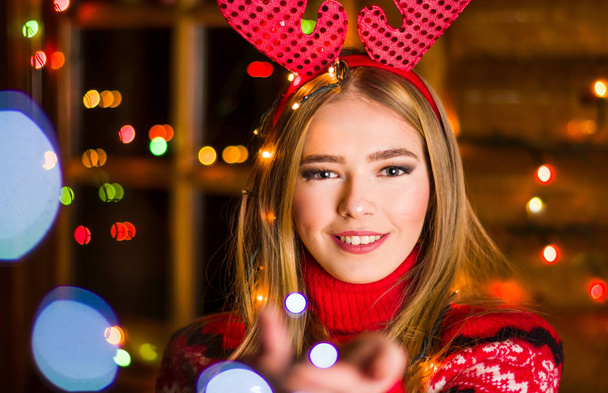 Красивая девушка с праздничными огнями в красном свитере
 - Фото, изображение