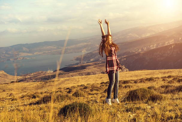 menina feliz desfrutando da natureza e do sol, mãos levantadas para cima
 - Foto, Imagem