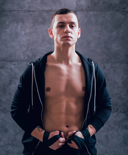 Young fighter posing in studio before grey wall - Foto, afbeelding