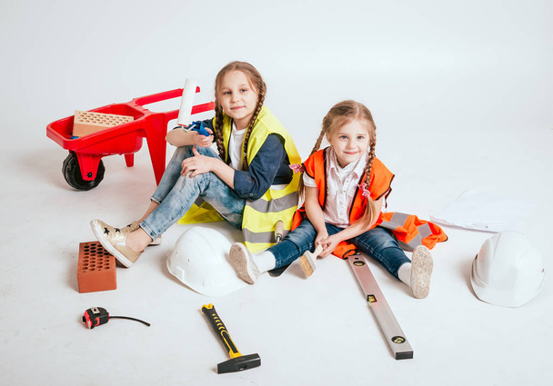 Two little cheerful girls with braids playing in repair or construction on white - Foto, Imagem