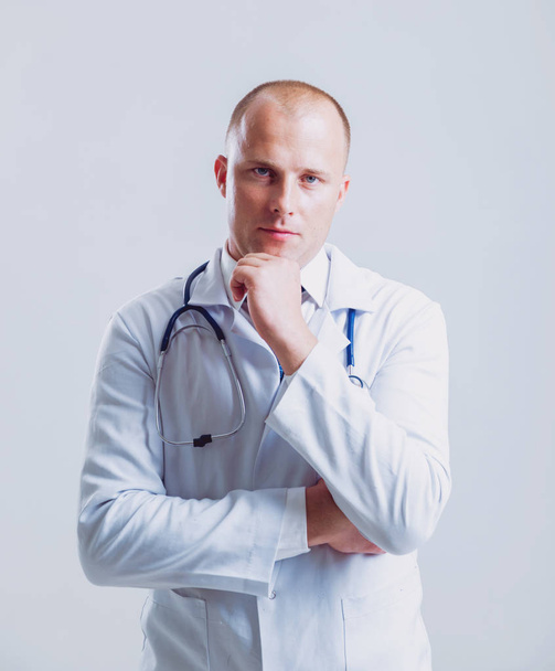 Adult caucasian blue eyed doctor posing with different medical things before white wall with copy space - Photo, Image