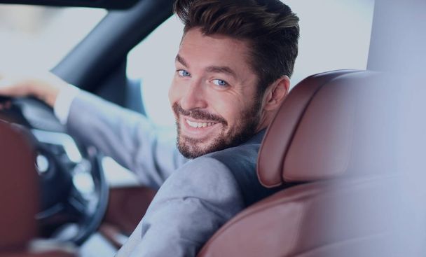 Portrait of an handsome smiling business man driving his car - Foto, afbeelding