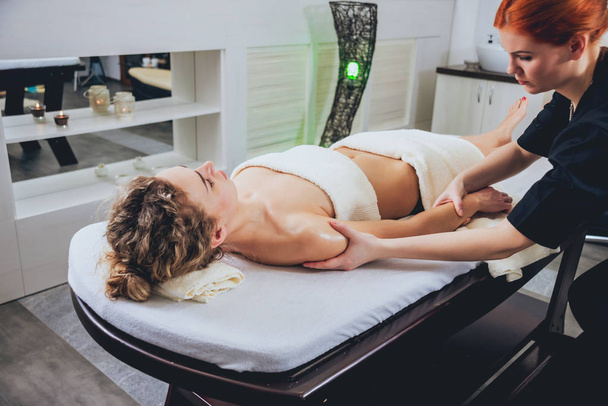 Young curly caucasian girl relaxing in spa. Body massage. - Fotó, kép