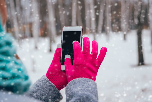 Woman using smartphone with pink gloves for touch screens in winter. - Φωτογραφία, εικόνα