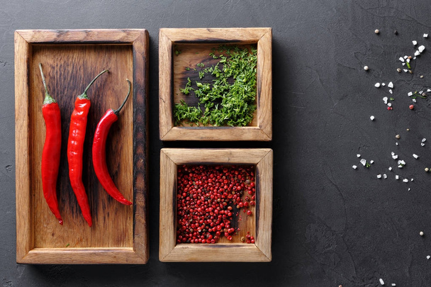 Diverse spices and chilli in wooden boxes on dark background, top view, copy space - Photo, Image