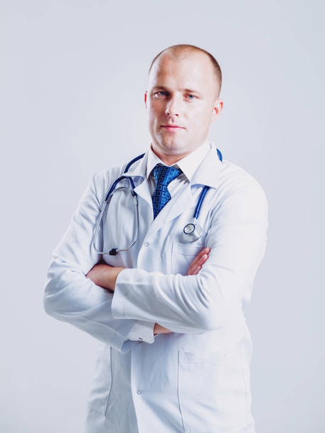 Adult caucasian blue eyed doctor posing with different medical things before white wall with copy space - Фото, зображення