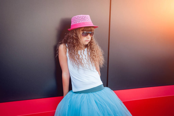 Little girl in pink hat and fancy blue skirt posing on street - Foto, afbeelding