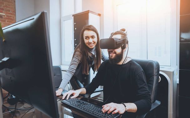 Young man with woman creative office workers testing VR goggles and having fun - Foto, afbeelding