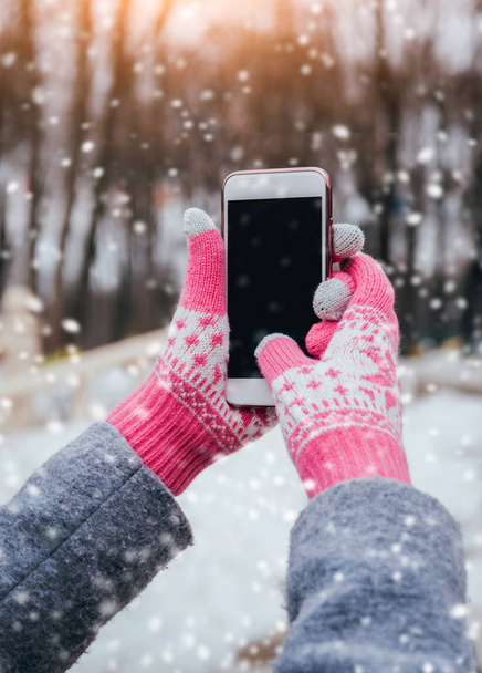 Woman using smartphone with pink gloves for touch screens in winter. - Fotoğraf, Görsel