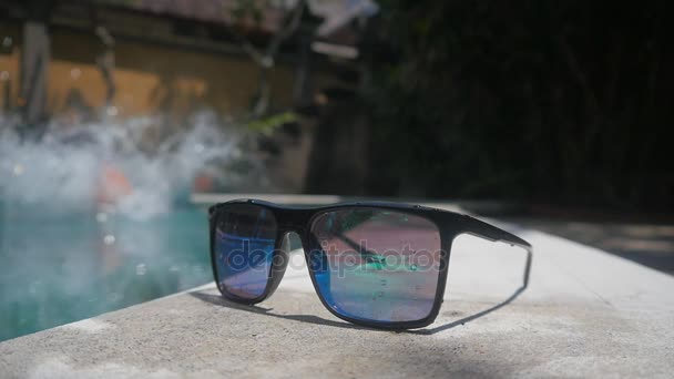 γκρο πλαν, γυαλιά ηλίου το καλοκαίρι, ο άνθρωπος άλματα στην πισίνα σε φόντο, δραστήριες διακοπές - Πλάνα, βίντεο