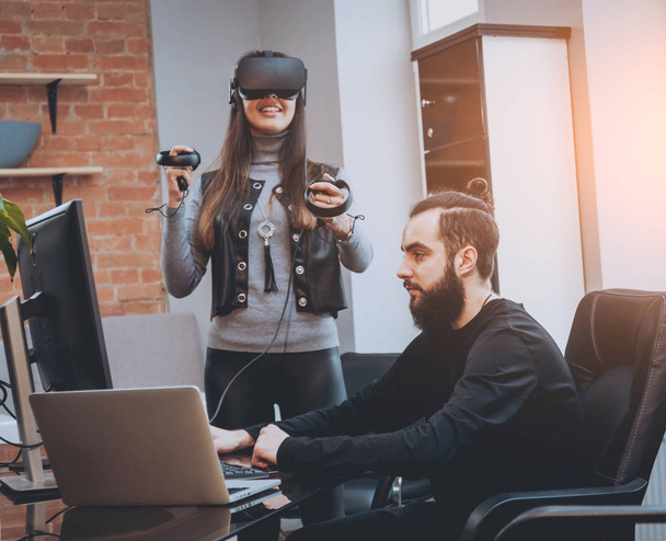 Young man with woman creative office workers testing VR goggles and having fun - Fotó, kép