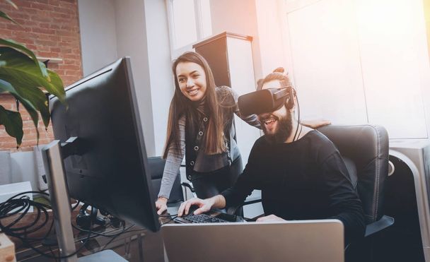 Young man with woman creative office workers testing VR goggles and having fun - Foto, Imagen